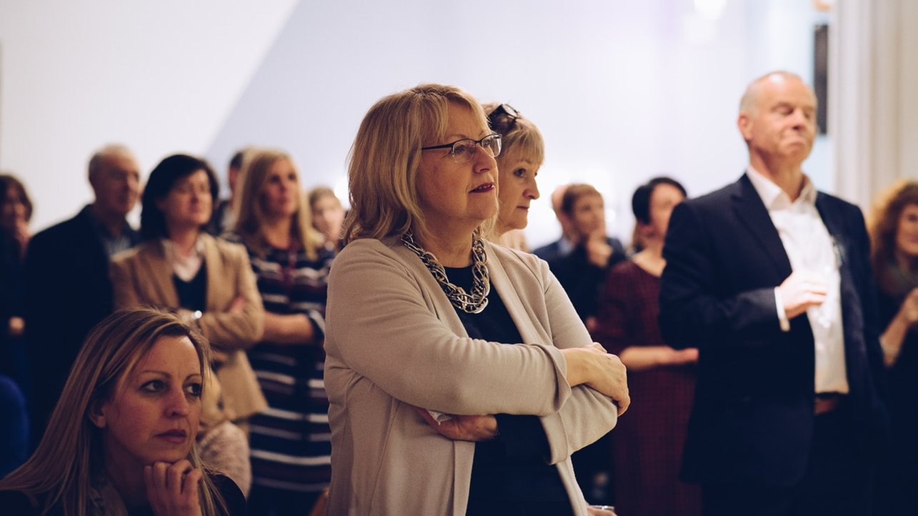 Colour image shows lady in a crowd listening to an address on strategic HR. 